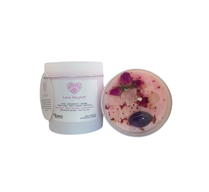 A white plastic jar labeled 'Love Magnet' with its lid placed beside it, showing a pink resin insert with embedded petals and a dark purple stone on a plain white background.