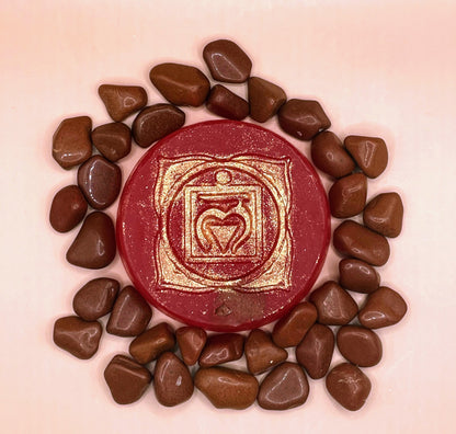 Red stone with gold emblem surrounded by smaller stones on a pink background