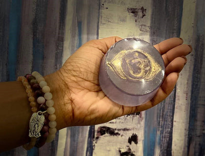 Hand holding a round, translucent object with gold designs against a patterned curtain background